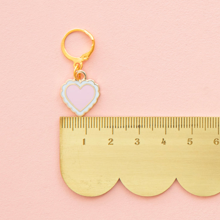 Gold keychain with heart charm on a gold ruler against a pink background
