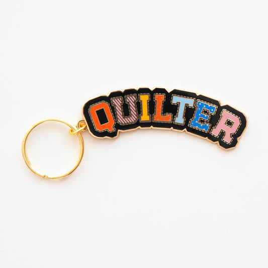 Keychain with colorful letters spelling 'QUILTER' on a white background