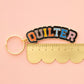Keychain with 'QUILTER' text on a pink background