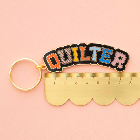 Keychain with 'QUILTER' text on a pink background