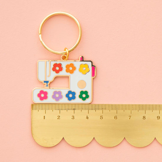 Keychain with sewing machine design and colorful flowers on a pink background