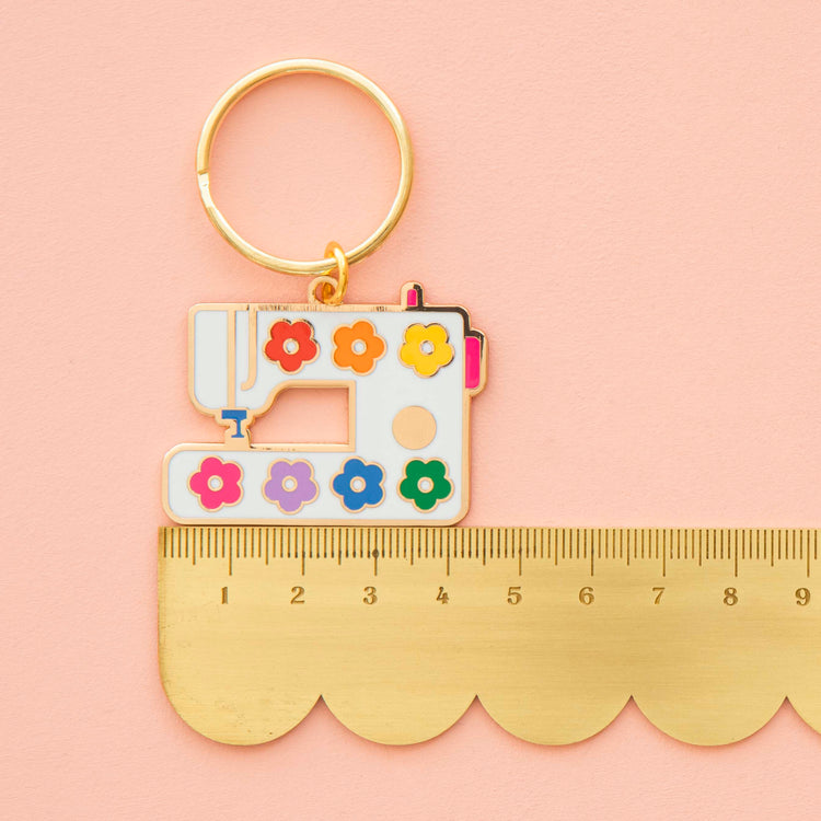 Keychain with sewing machine design and colorful flowers on a pink background
