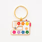 Keychain shaped like a sewing machine with colorful flowers on a white background